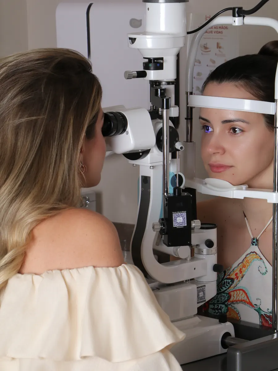 Dra. Maria Isabel examinando os olhos de uma paciente na lâmpada de fenda