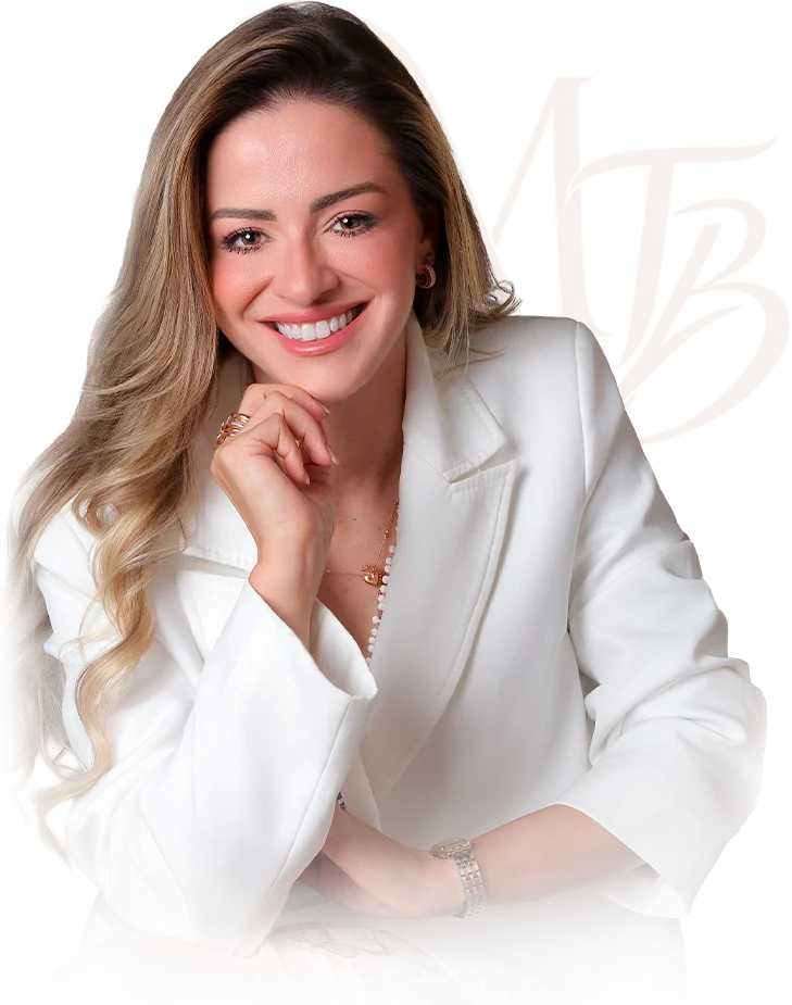 Dra. Maria Isabel Tom Back sorrindo, de blazer branco, com a mão no queixo