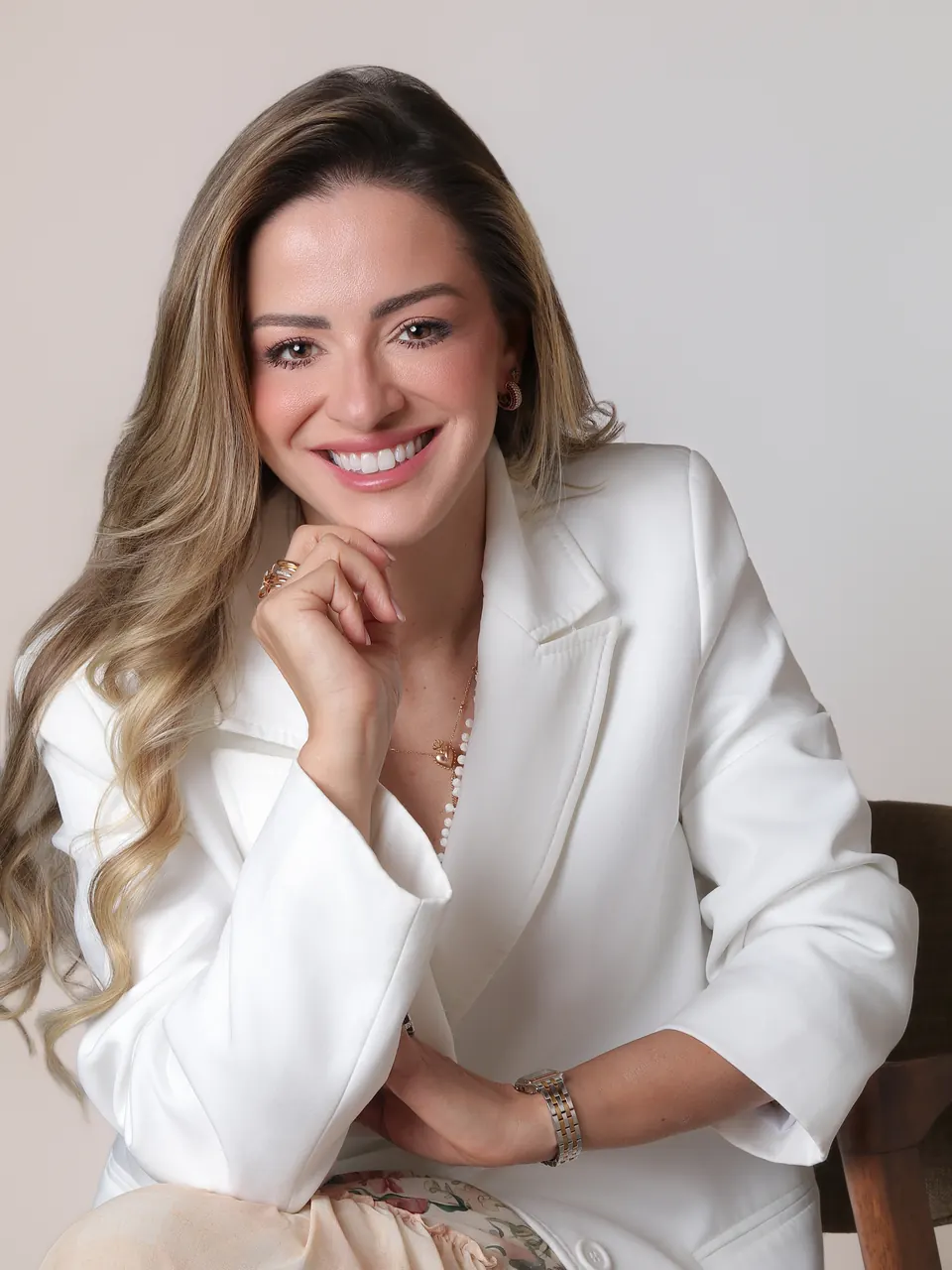 Dra. Maria Isabel Tom Back sentada, sorrindo, de blazer branco